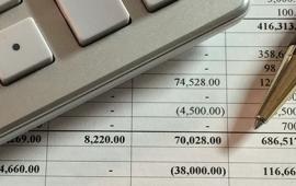 spreadsheet with columns and figures, calculator and pen