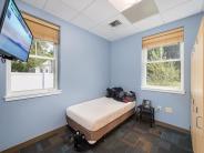 Blue walled room with two windows with a twin sized bed