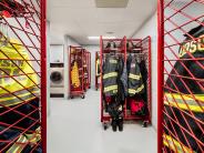 Red metal racks with firefighter gear handing on the rack