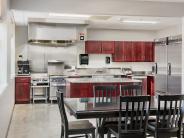 Black table with six chairs with a stainless steel appliance kitchen behind it with cherry cabinets