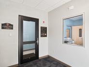 Lobby entrance, black glass door with a wall to the right with a window in the middle.