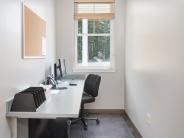 Grey walls with desk top mounted on left wall and window at the end of the room.