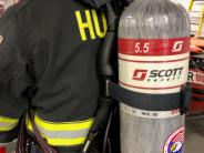 Photo of the back of a Firefighter with a grey cylinder oxygen tank strapped onto his back