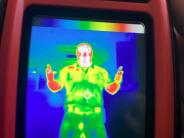 Orange handheld thermal imaging camera.  Display shows outline of body.