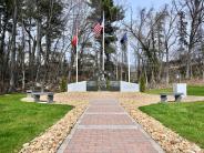 Brick pathway lined with tan rocks facing a granite memorial.