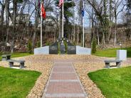 Brick pathway lined with tan rocks facing a granite memorial.