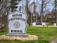 Granite stone reading Hudson Firefighters Memorial with last alarm logo in middle sitting on a marble stone.