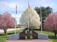 Firefighters Memorial - three piece granite and stone structure with pink and white flowering trees behind it.