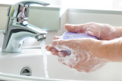 Person with soapy hands rinsing under a sink