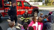 Photo of the apparatus and a firefighter explaining to children what they do.